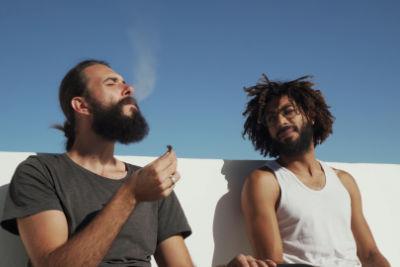 Two friends smoking a joint together with their eyes closed